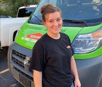 Young woman w/ long brown hair, SP shirt w/ green truck in background