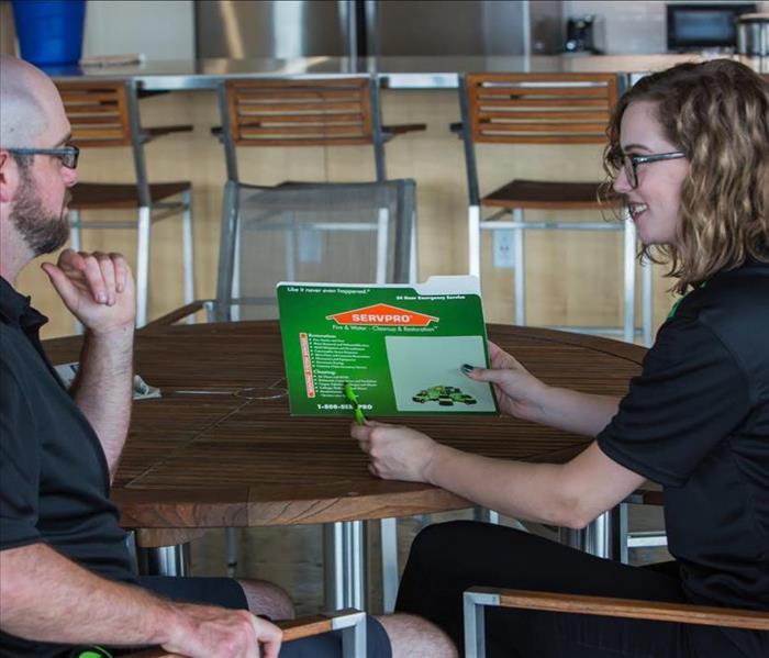 SERVPRO technician sharing pamphlet with client 