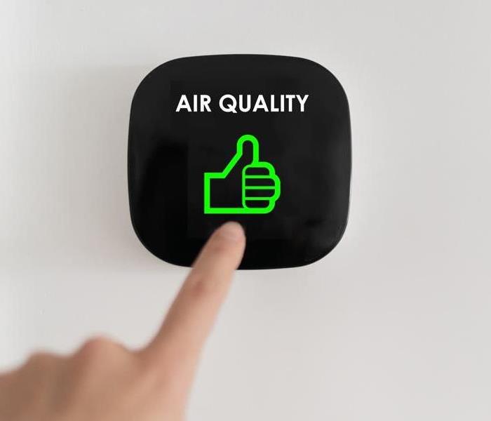 A finger points to an air quality marker on a smart thermostat.