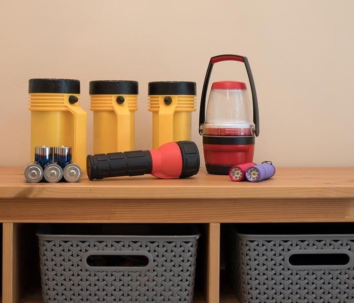 Flashlights, batteries, and other lights sit on a shelf.
